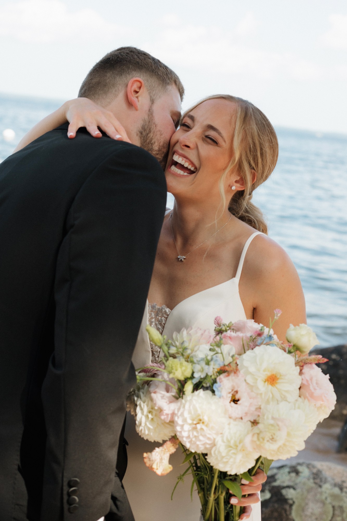 Bride and groom laughing by the water
