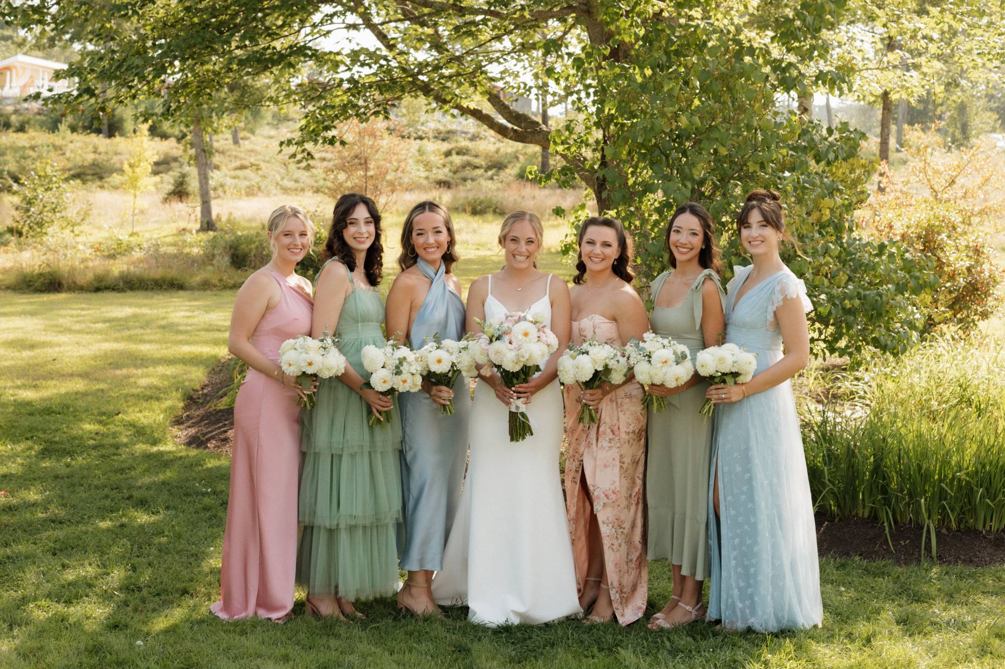 The wedding party in soft pastels beneath the trees